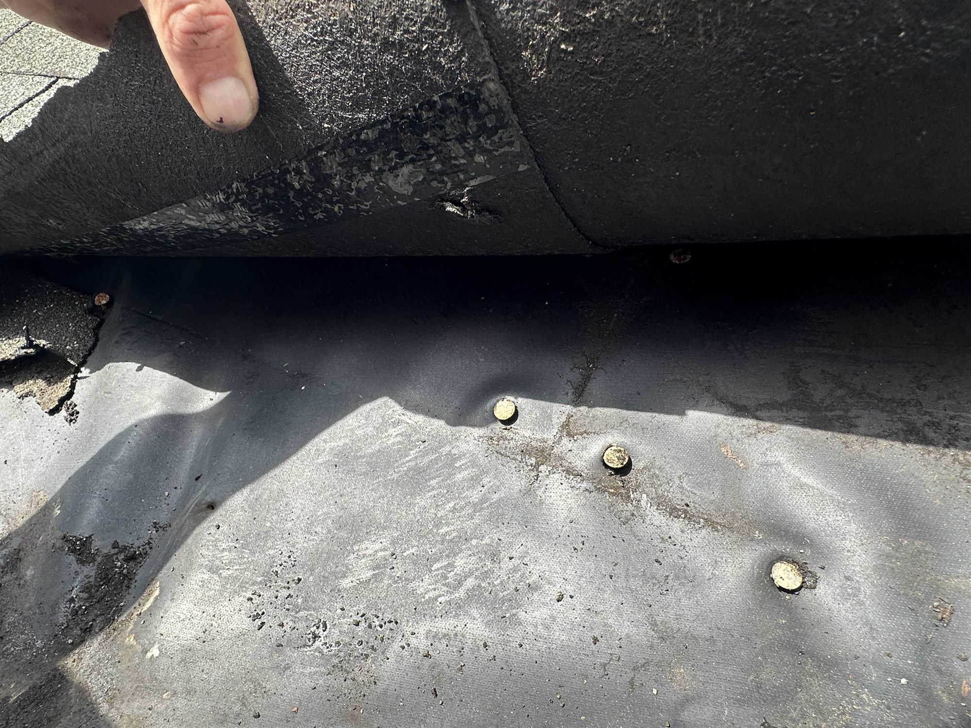 Lifting an aged roof membrane to reveal exposed fasteners and a void beneath