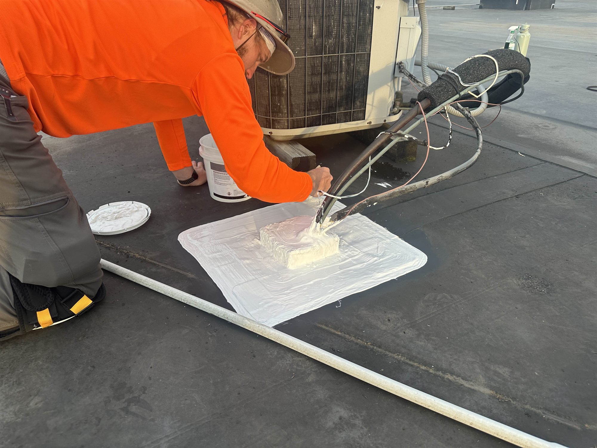 Roofer sealing a pipe penetration on a flat roof in Allentown PA