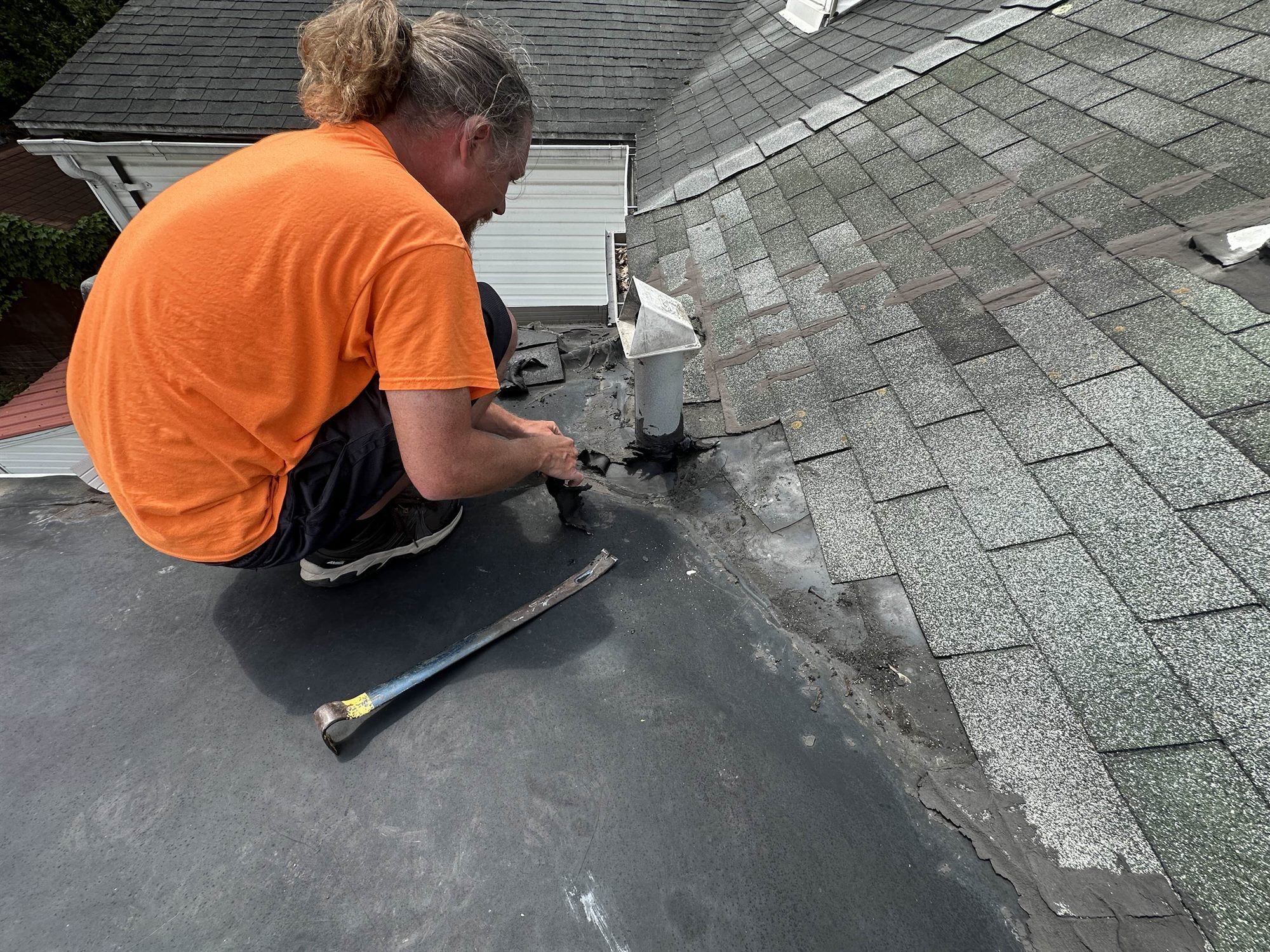 Roofer repairing a leaking pipe flashing on a roof in Coatesville PA
