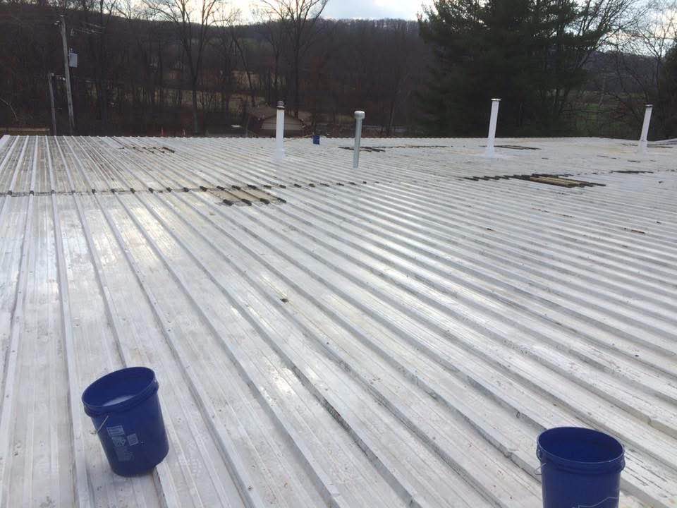 Large commercial metal roof being prepped and coated with silicone
