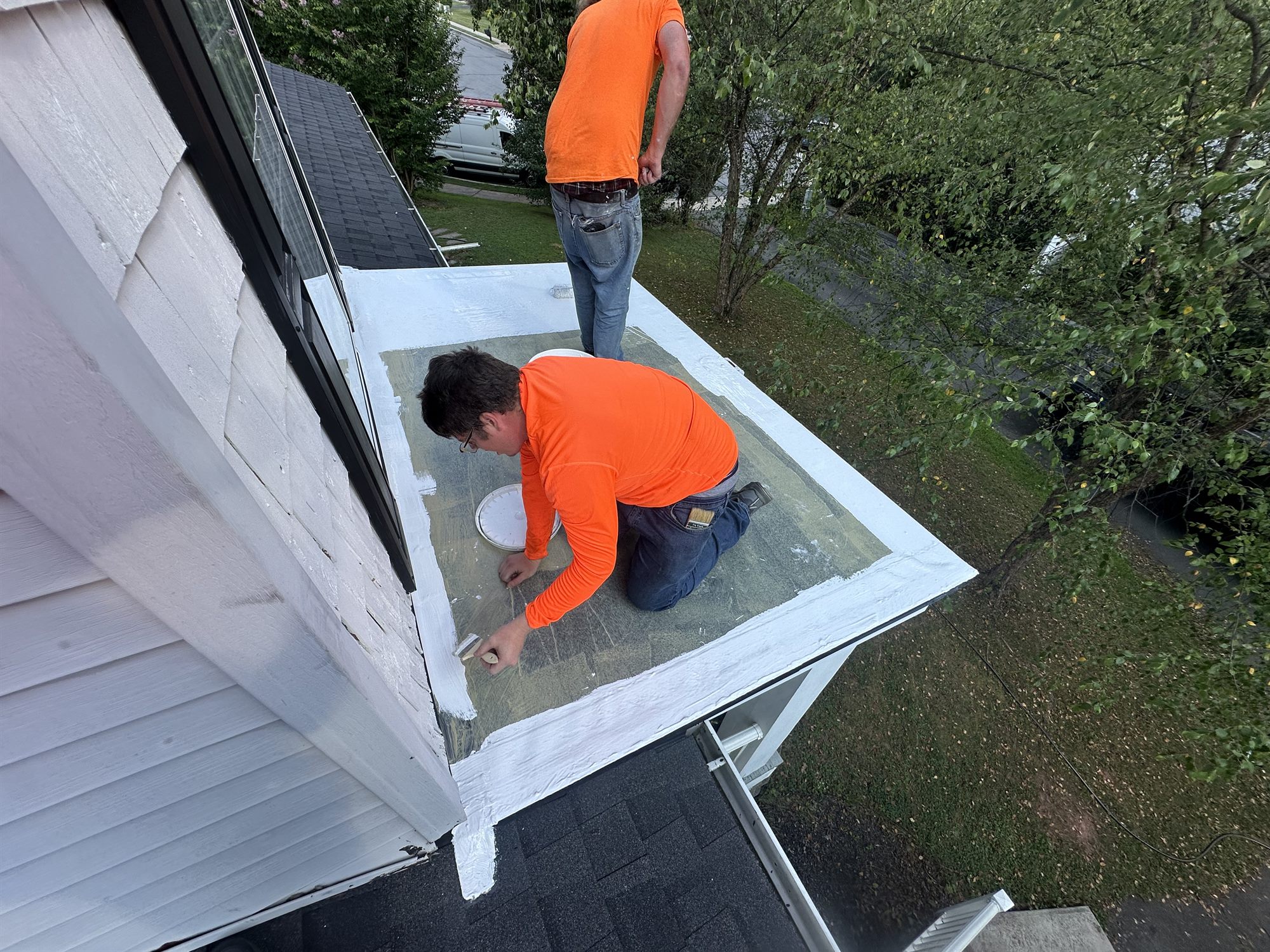 Two roofers detailing the seams on a residential flat roof