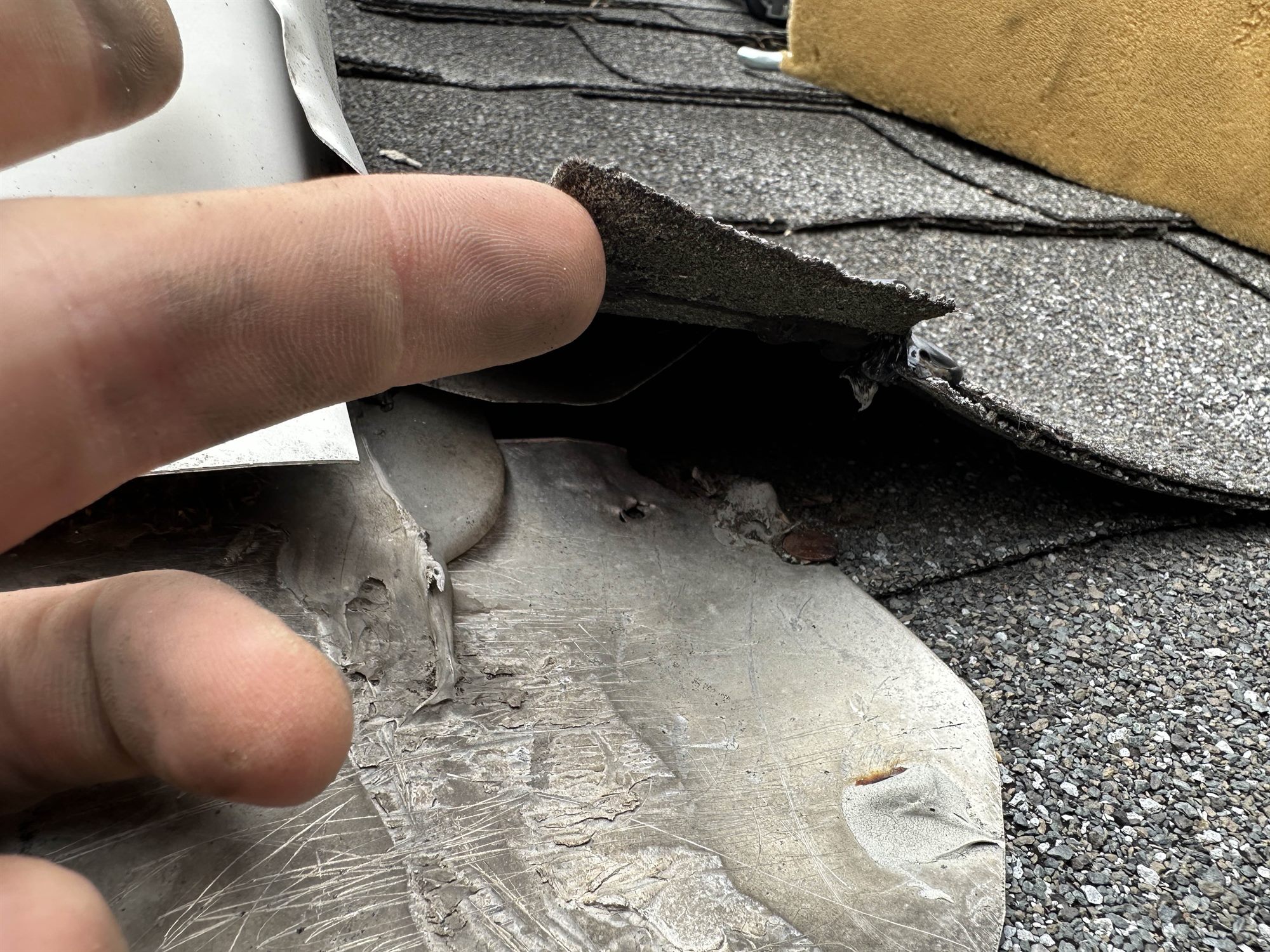 Inspecting a failed, lifting pipe flashing at a roof transition