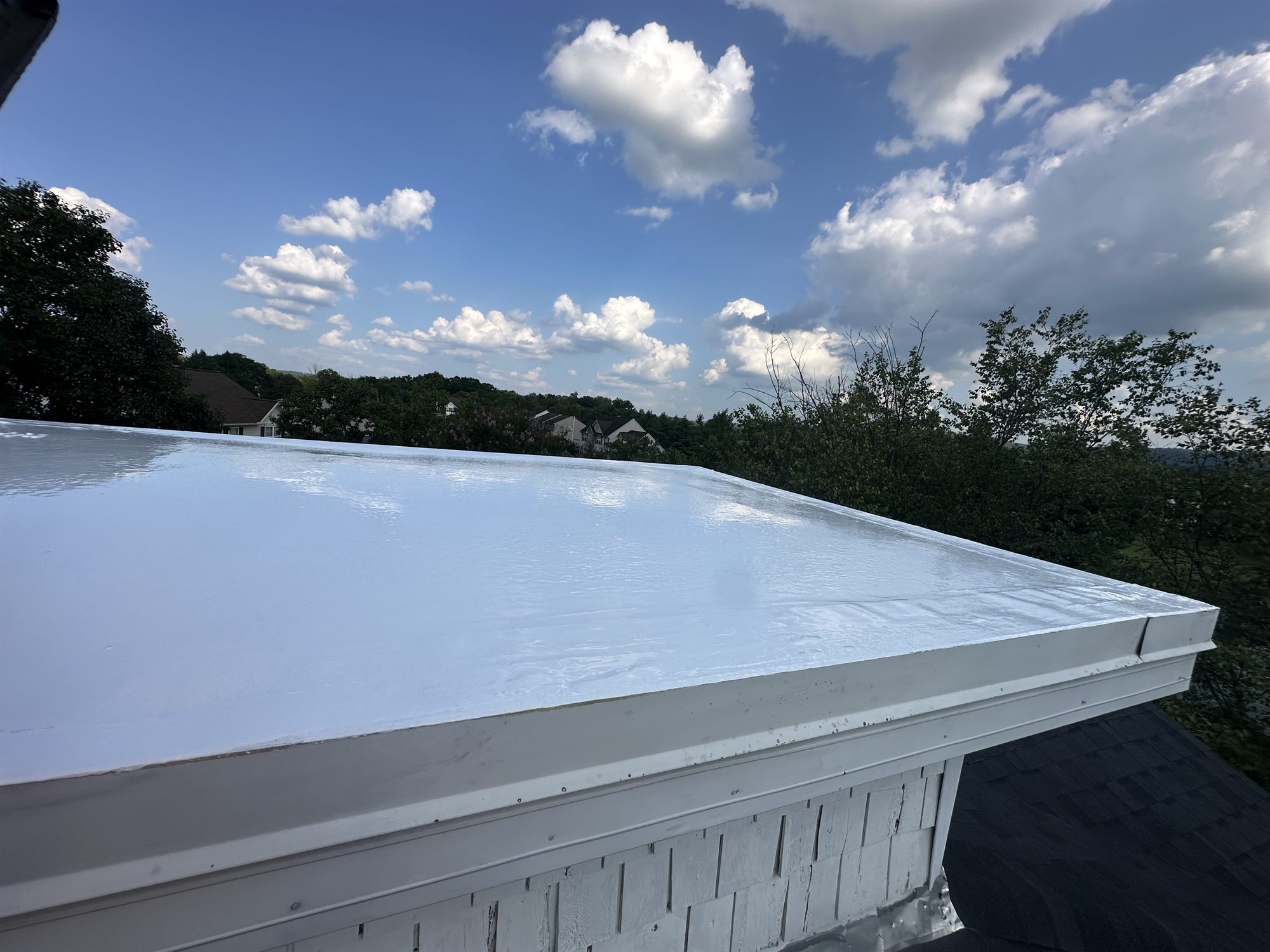 Glossy white silicone flat roof finished on a hilltop home