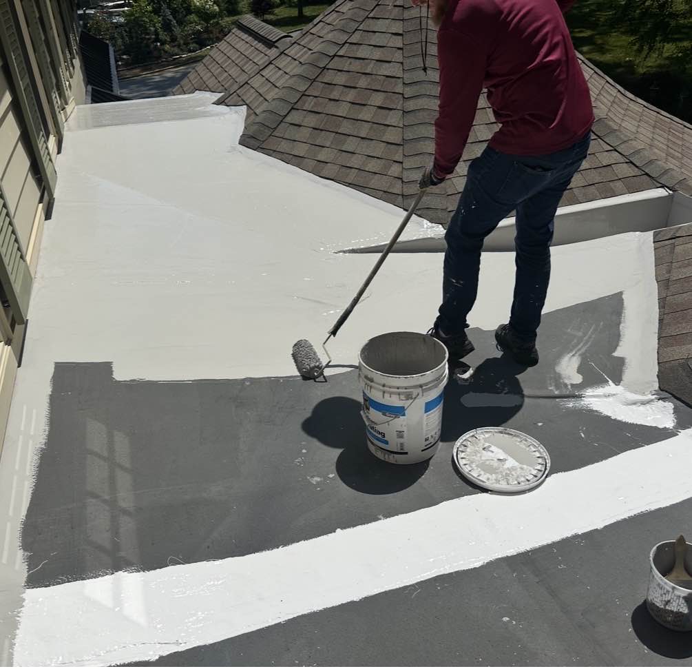 Rolling white silicone coating across a residential flat roof