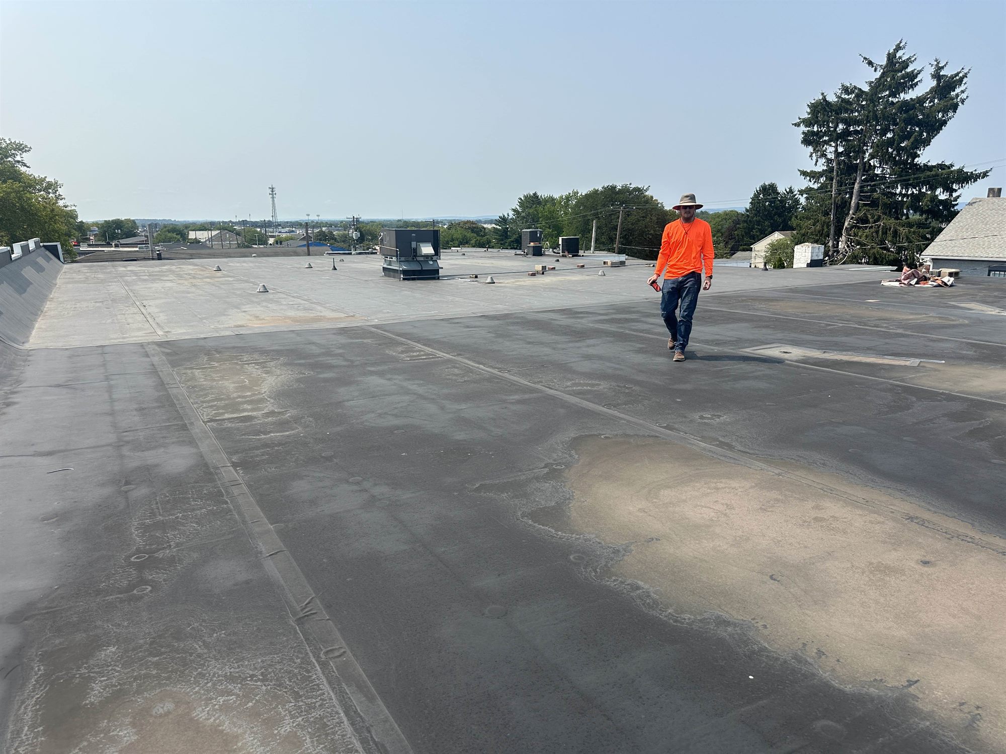 Roofer walking and inspecting a large aged commercial flat roof