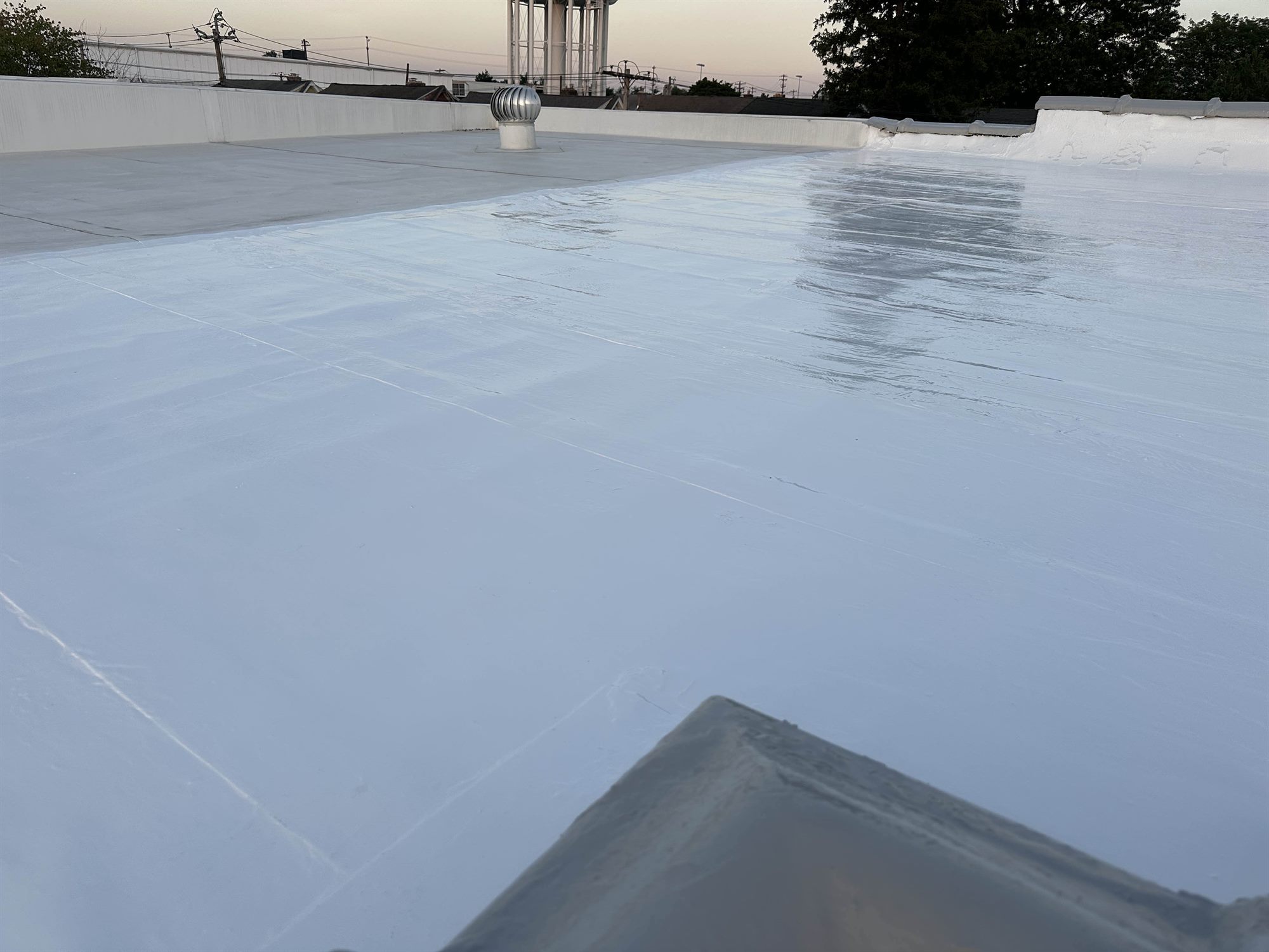 Lansdale PA flat roof after bright white silicone coating at dusk