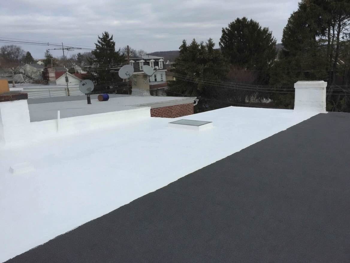 Bright white silicone coating applied over a black modified bitumen roof