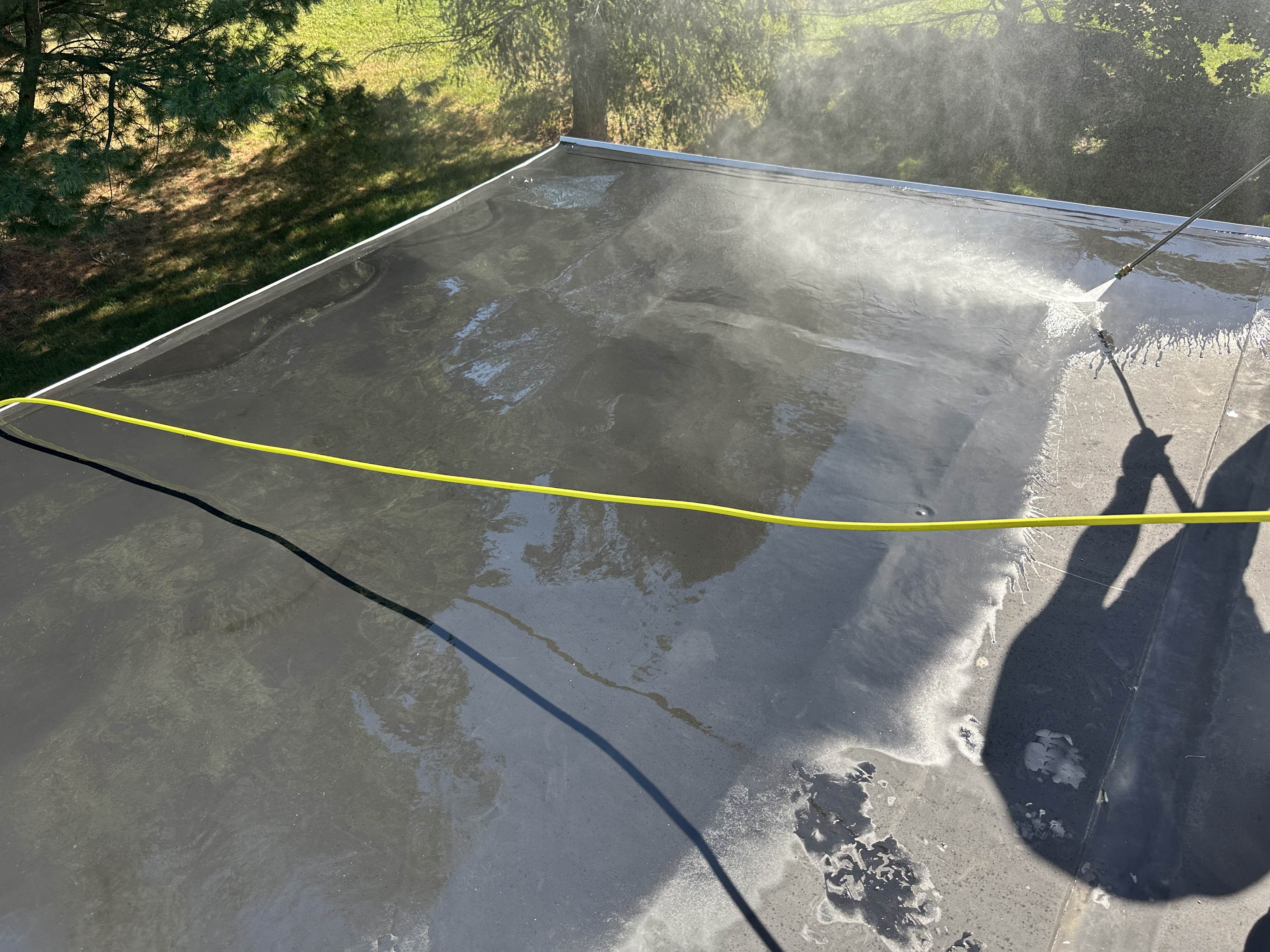 Power washing a rubber flat roof before silicone coating