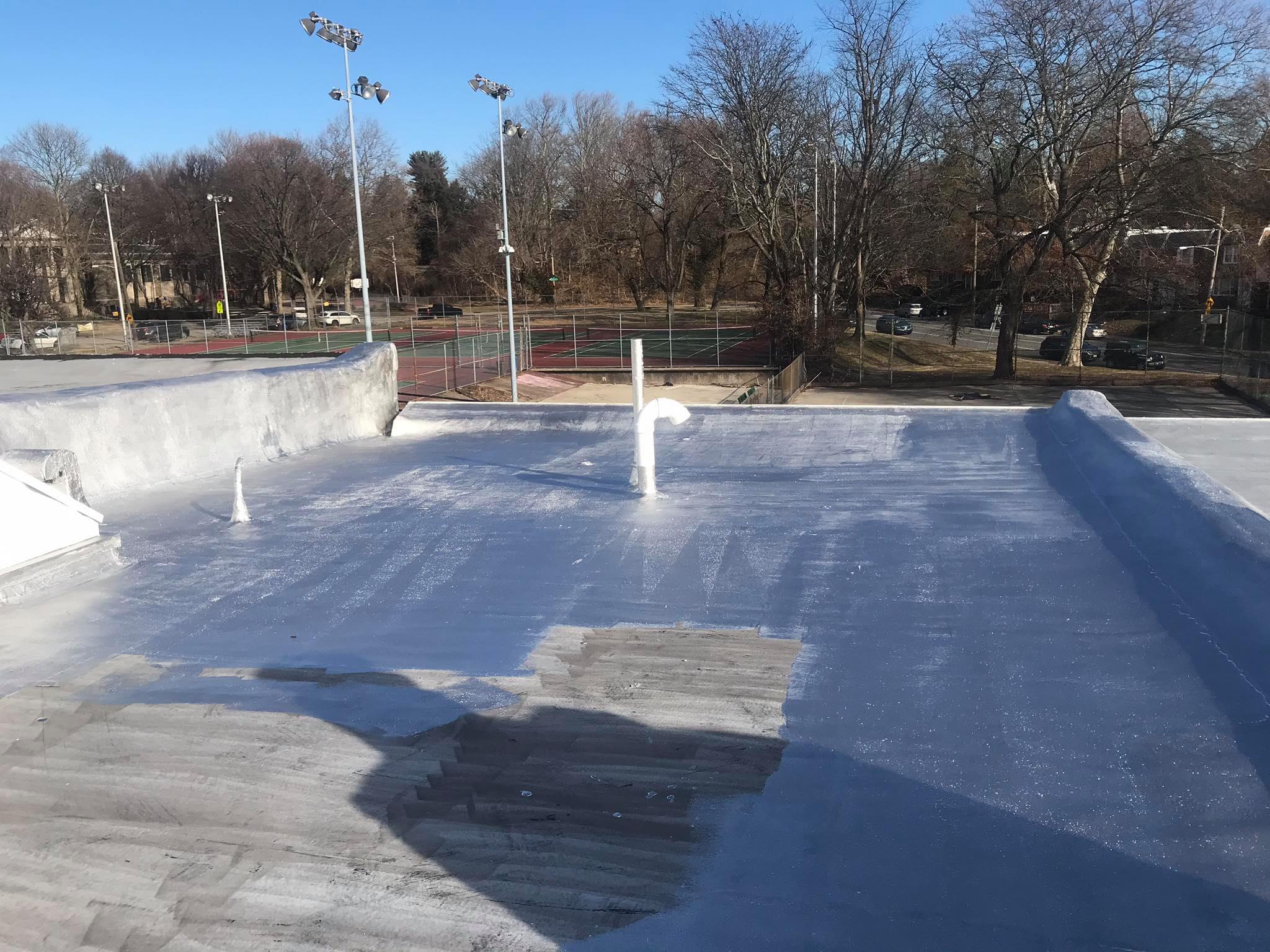 Aluminum roof coating mid-application, half the modified bitumen surface coated bright silver